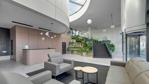 Eine moderne Lobby mit Sitzgelegenheiten, einem Empfangsbereich und einer Treppe zu einer oberen Ebene.