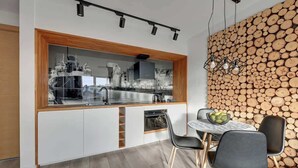 A modern kitchen with a built-in island, white cabinetry, and a dining area with a round table and chairs. - Nº 53 | Pool, SPA & Gym (Gdańsk)