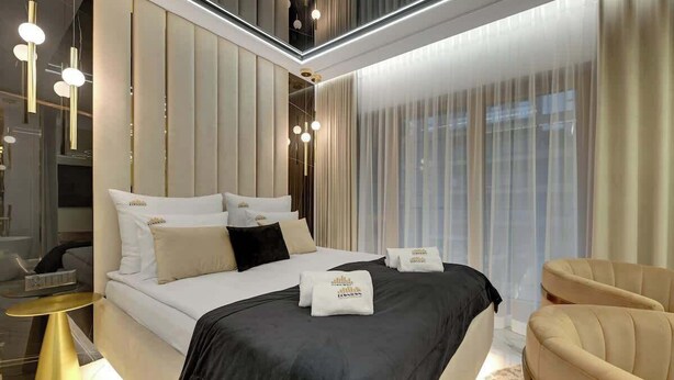 A modern hotel room with a large bed, bedside tables, a seating area, and a view through the window. - Nadmotławie124 | Romantic Stay | Riverside & Sauna (Gdańsk)