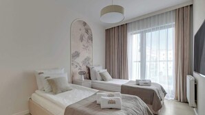 Hotelkamer met twee bedden, een groot raam met gordijnen, een flatscreen televisie en een kunstwerk aan de muur.