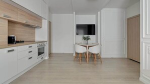 Een moderne keuken met witte kastjes, een houten aanrechtblad en een eethoek met een ronde tafel en vier stoelen.