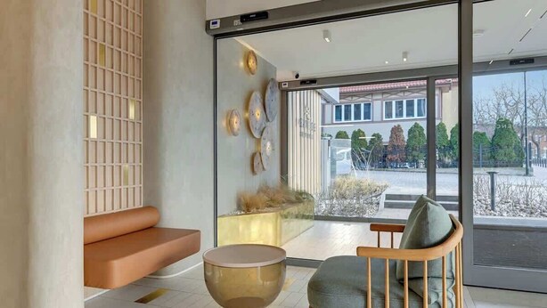 Un intérieur moderne avec un espace salon, une cloison en verre et une vue sur l’extérieur.