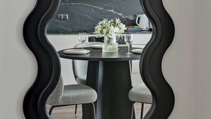 A modern kitchen with wooden cabinets, a black marble backsplash, and a dining area with a table set for two. - Scala 37 with Balcony | City Center | Parking (Gdańsk)