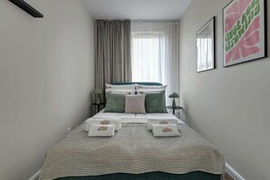 A neatly arranged hotel room with a bed, pillows, a bedside table, a lamp, and a window with curtains. - Scala 37 with Balcony | City Center | Parking (Gdańsk)