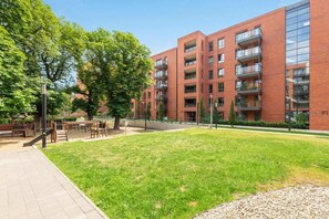 A multi-story building with a brick facade, outdoor seating area, and a grassy courtyard. - Scala 37 with Balcony | City Center | Parking (Gdańsk)