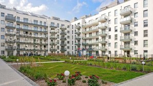Ein mehrgeschossiges Wohngebäude mit Balkonen, einem zentralen Innenhof mit Pflanzen und einem Spielplatz.