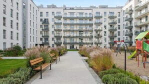 Ein Wohngebäude mit mehreren Balkonen, einem zentralen Weg und einem Spielplatz.