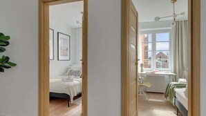 Quarto com cama, escrivaninha, cadeira e janela com cortinas.