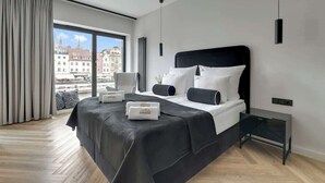 Moderni hotellihuone, jossa on suuri sänky, yöpöytä, työpöytä ja näkymä kaupunkiin.