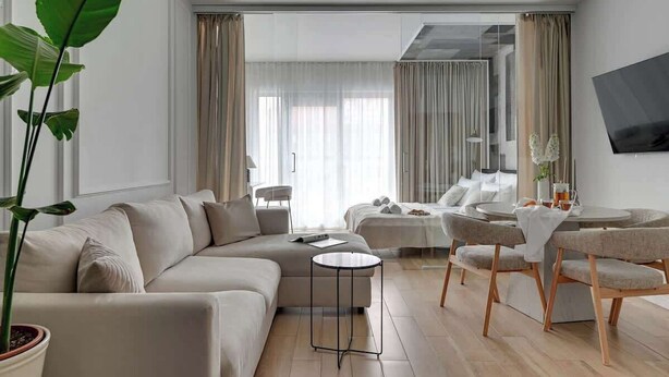 A modern living room with a sofa, a round coffee table, and a dining area with chairs. - Waterlane E2 | Spa, Pool & Gym | Riverside (Gdańsk)