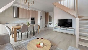 Een moderne woonkamer met een eethoek, keuken en een televisie.
