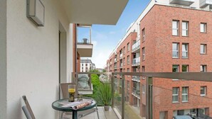 A balcony with a table, chairs, and a potted plant. - Waterlane F12 | Spa, Pool & Gym | Riverside (Gdańsk)