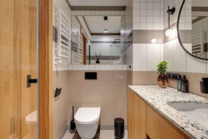 Ein modernes Badezimmer mit Toilette, Waschbecken und Spiegel.