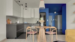 Moderni keittiö, jossa on harmaat kaapit, pyöreä puinen pöytä ja kaksi tuolia.