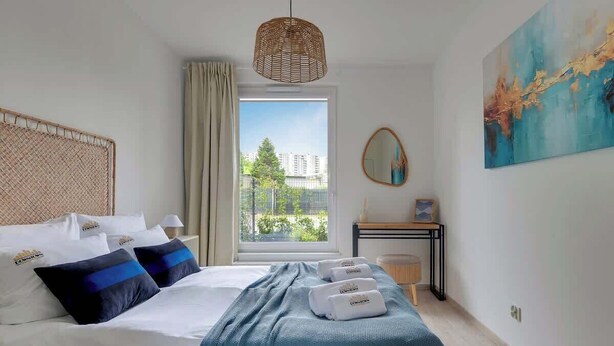 Hotellihuone, jossa on sänky, työpöytä, ikkuna, josta on näkymä, ja taulu seinällä.