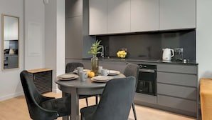 A modern kitchen with grey cabinets, a dining table with chairs, and a coffee maker. - Scala K3 | Garden | Best Location (Gdańsk)