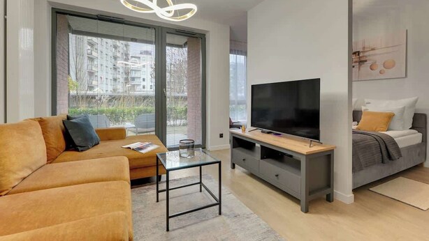 A modern living room with a sofa, TV, and a glass table. - Scala K3 | Garden | Best Location (Gdańsk)