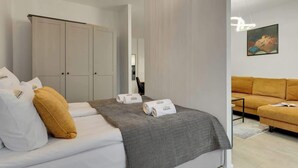 A modern hotel room with a bed, a wardrobe, a sofa, and a painting on the wall. - Scala K3 | Garden | Best Location (Gdańsk)