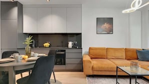 A modern kitchen with grey cabinets, a dining table with chairs, and a sofa with cushions. - Scala K3 | Garden | Best Location (Gdańsk)