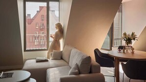 A modern living room with a sofa, a dining table, and a window with blinds.