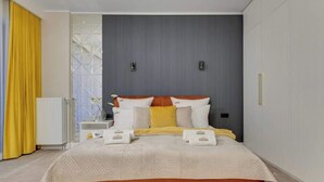 A modern hotel room with a large bed, a bedside table, a nightstand, and a window with curtains. - Granaria B106 | Hotel Standard Apartment (Gdańsk)