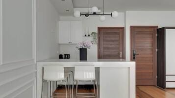 Eine moderne Küche mit weißen Schränken, einer Holztür und einer Bar mit weißen Hocker.