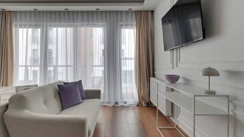 Ein modernes Wohnzimmer mit einer Couch, einem Flachbildfernseher an der Wand, einer Heizung und einem Beistelltisch.