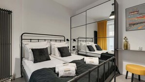 A modern hotel room with a large bed, a bedside table, a mirror, and a window with curtains. - Granaria A212 | Best Location (Gdańsk)