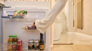 Eine Person öffnet einen Kühlschrank, der mit verschiedenen Getränken und Snacks gefüllt ist.