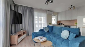 Un soggiorno moderno con un divano blu, un tavolino in legno e un televisore su un mobile.