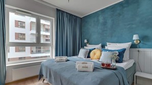 Una camera da letto con un letto grande, vista sugli edifici esterni e una finestra con tende.
