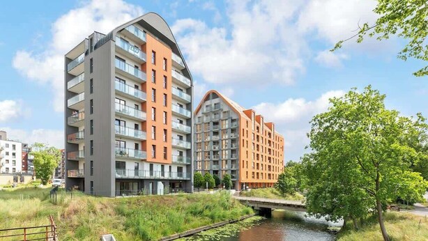 Un edificio de apartamentos moderno con balcones, un río y un puente.