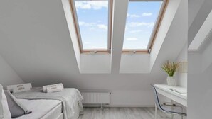 Un dormitorio moderno con tragaluz, una cama, un escritorio y un radiador.