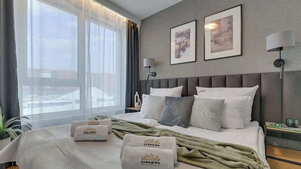 Camera d'albergo con un letto grande, due quadri appesi al muro, una lampada da comodino e vista sull'esterno.