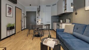 Un soggiorno moderno con un divano blu, un tavolo da pranzo con sedie e una zona cucina con pensili e un piano di lavoro.