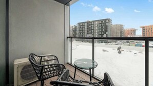 Un balcone con vista su un cantiere edile e edifici, un tavolo e due sedie.