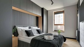 Een moderne slaapkamer met een bed, nachtkastje en raam.