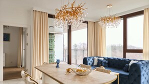 A modern living room with a blue sofa, a marble dining table, and a chandelier.