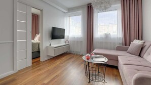 Ein modernes Wohnzimmer mit einer Couch, einem Fernseher, einem kleinen Tisch und einem weißen Schrank.