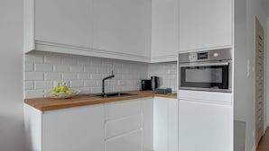 Eine moderne Küche mit weißen Schränken, einer Holz Arbeitsplatte, einem Einbauofen und einem Spülbecken.