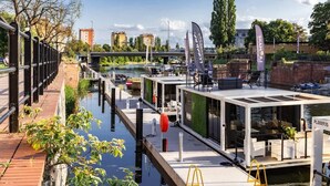 Ein schwimmendes Restaurant mit Außenbereich, einem Anlegesteg und Blick auf den Fluss sowie die Stadtlandschaft.