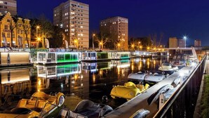 Una marina di notte con barche ormeggiate, un servizio di taxi acqueo e edifici sullo sfondo.