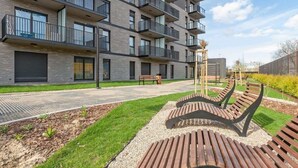 Een modern appartementencomplex met balkons, een verhard looppad en buiten zitplaatsen.