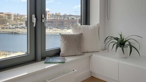 Une pièce avec une grande fenêtre, un radiateur blanc, une armoire blanche et une plante.