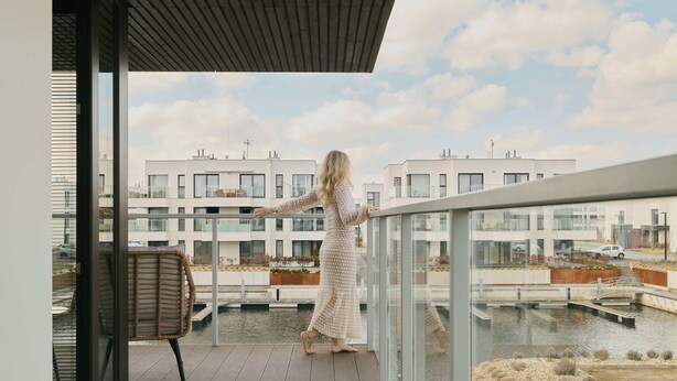 A balcony with a view of a modern building complex and a water body. - Sol Marina Harmony | Perfect View (Gdańsk)