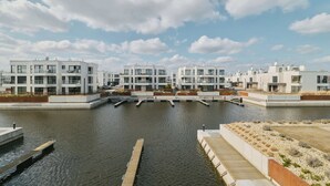 A modern residential complex with multiple buildings, a canal, and a wooden dock. - Sol Marina Harmony | Perfect View (Gdańsk)