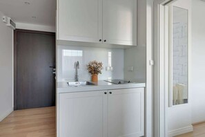 A modern kitchen with white cabinetry, a built-in sink, and a small countertop. - Tartaczna 17 | Perfect Stay (Gdańsk)