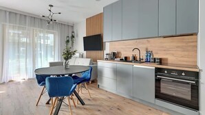 Eine moderne Küche mit Essbereich, einem über der Arbeitsplatte montierten Fernseher und einem großen Fenster mit durchsichtigen Vorhängen.