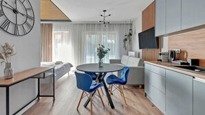 Eine moderne Küche mit Essbereich, einer großen Uhr und einer Couch.