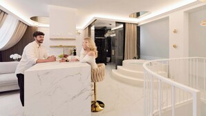 Een moderne hotel lobby met een marmeren receptiebalie, een zithoek met een bank, en een trap.